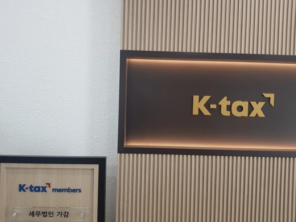 강남지점 목재 패널 벽면에 설치된 K-tax 사인