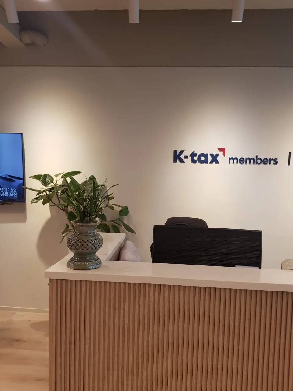 K-tax members 로고가 있는 사무실 접수 데스크와 화분